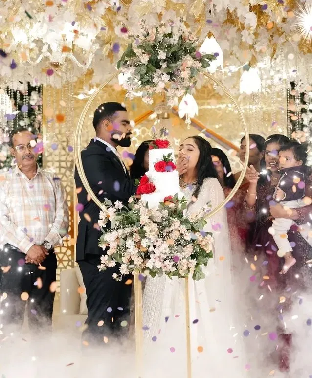 Couple cutting the cake surrounded by family and confetti