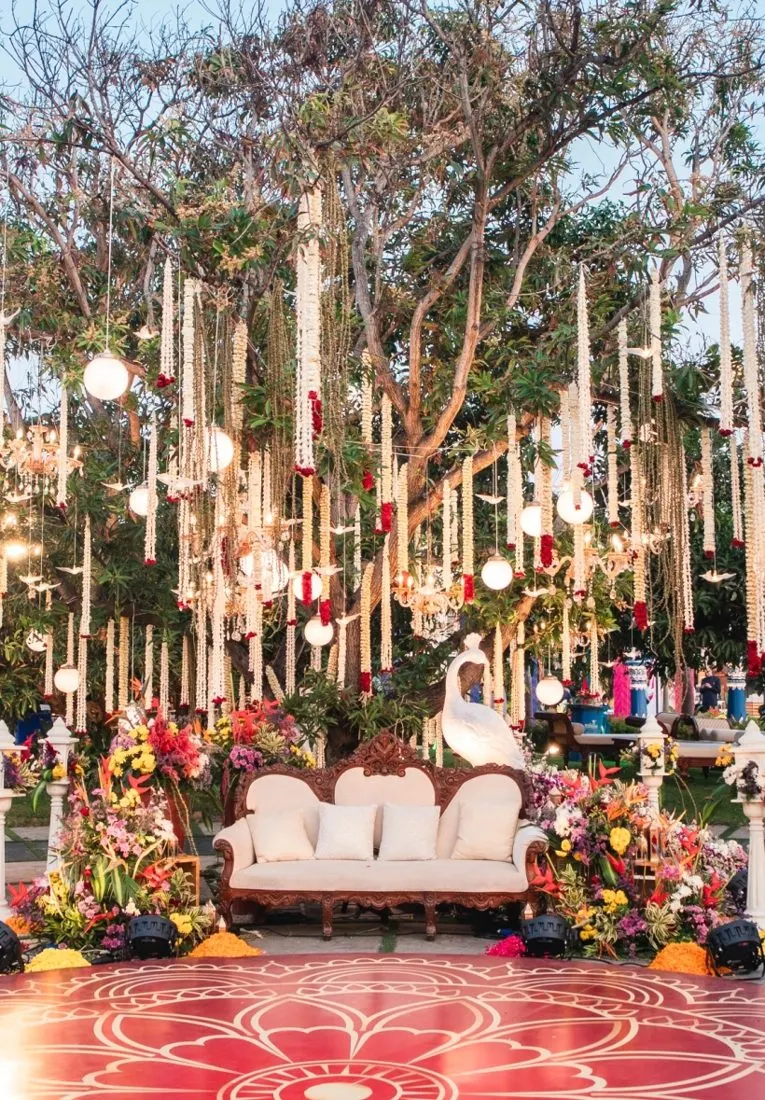 Garden wedding stage with hanging lights and a red floral carpet