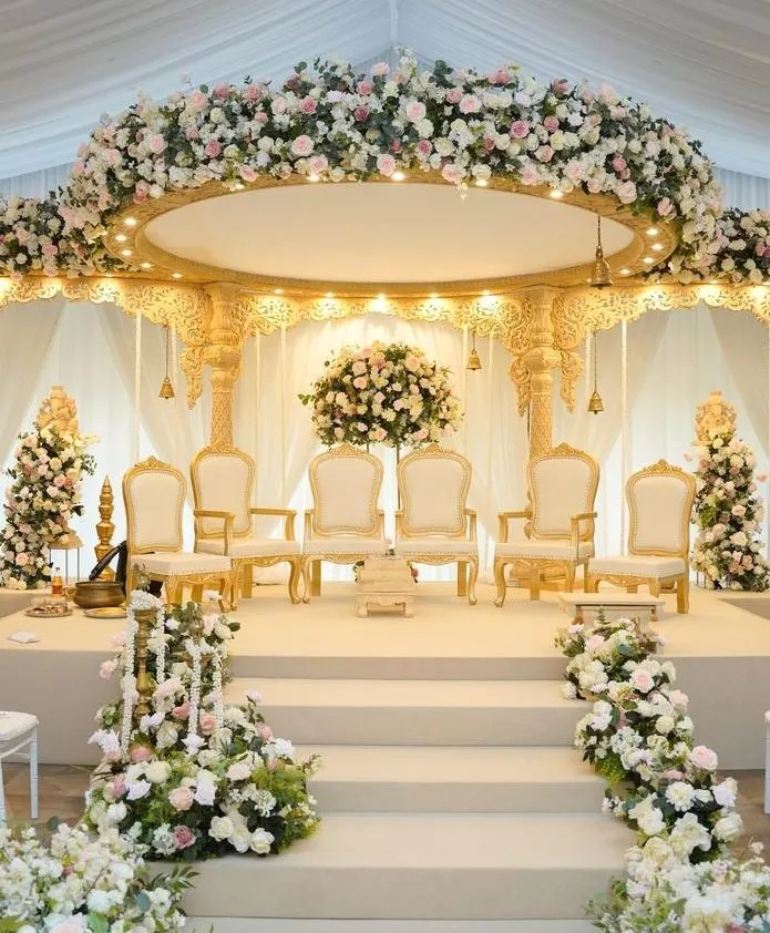 Gold and white wedding stage with floral canopy and royal seating