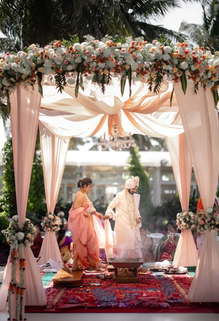 Couple walking the pheras around the sacred fire under a draped mandap