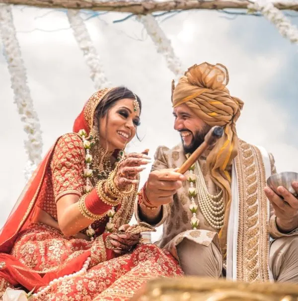 Bride and groom in red and gold sharing a laugh during the rituals