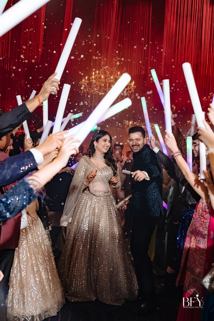 Couple dancing at their sangeet through a crowd waving light sticks