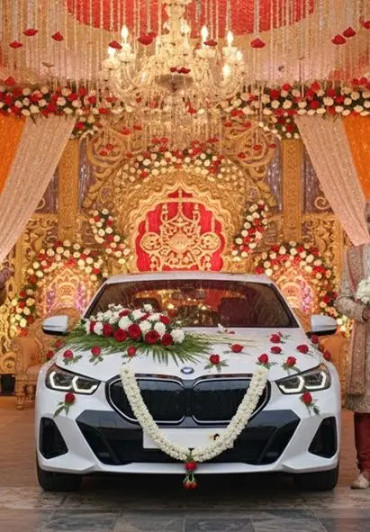 Flower-decorated wedding car in front of a floral stage